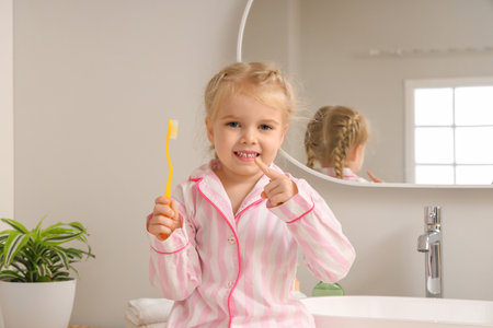 Cute little girl pointing at toothbrush in bathroomの写真素材