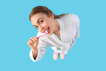 Beautiful young woman brushing teeth on blue backgroundの写真素材