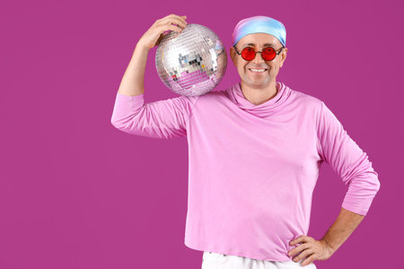Cool mature man with disco ball on purple backgroundの写真素材