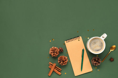 Cup of coffee with blank notebook and pine cones on green backgroundの写真素材