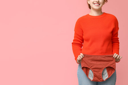 Beautiful young woman with period panties on pink background, closeupの写真素材