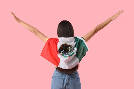 Young woman with Mexican flag on pink background, back viewの写真素材