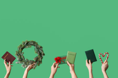 Female hands holding passports with Christmas decor on green background. New year vacation conceptの写真素材