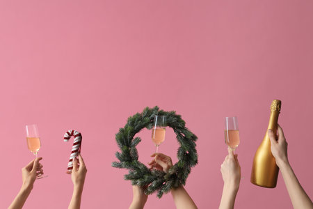 Female hands with glasses of champagne and wreath on pink backgroundの写真素材