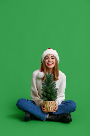 Happy young woman with Christmas tree on green backgroundの写真素材