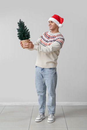 Young man in Santa hat with Christmas tree on white backgroundの写真素材