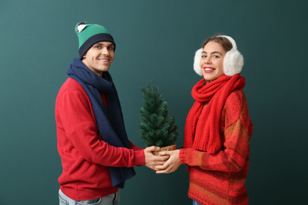 Happy young couple with Christmas tree on green backgroundの写真素材