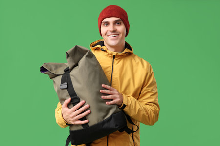 Young man in yellow stylish jacket and hat with bag on green backgroundの写真素材