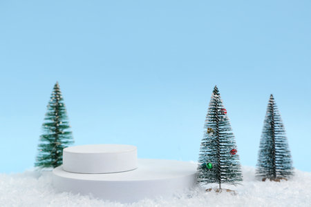 Decorative podiums with Christmas trees on snow against blue backgroundの写真素材