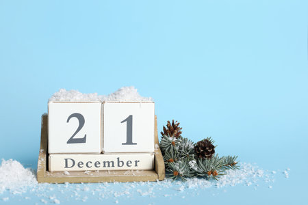 Cube calendar with date of winter solstice, fir branches and snow on blue backgroundの写真素材