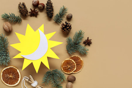 Paper sun with fir branches, dried oranges, cones and nuts on beige background. Winter solstice conceptの写真素材