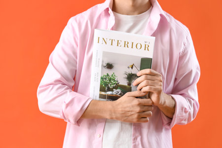 Young man with magazine on orange background, closeupの写真素材