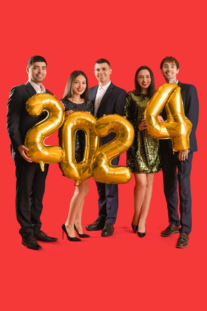 Group of young people with figure 2024 on red background. New Year celebrationの写真素材