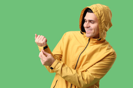 Young man in yellow stylish jacket on green background