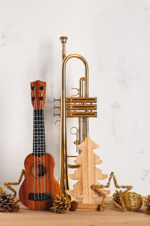 Composition with ukulele, trumpet and Christmas decorations on wooden table against light backgroundの写真素材