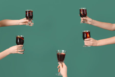 Frame made of female hands with glasses of warm mulled wine on green backgroundの写真素材