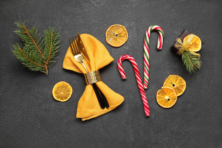 Dried orange slices with Christmas candy canes and cutlery on black backgroundの写真素材
