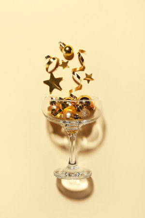 Champagne glass with Christmas decor on light yellow backgroundの写真素材