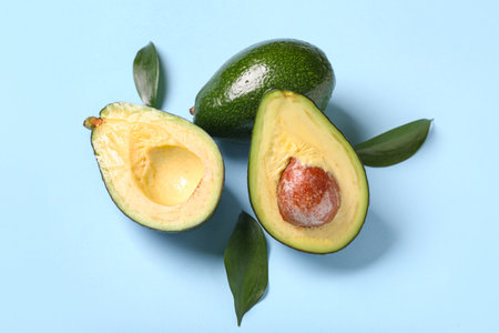 Fresh ripe avocados and leaves on blue backgroundの写真素材