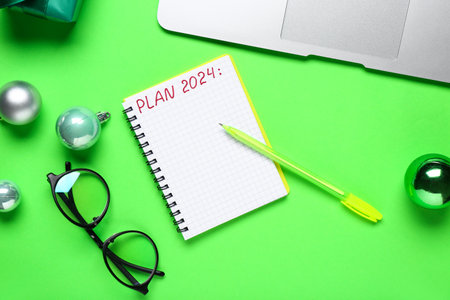 Notebook with text PLAN 2024, pen and eyeglasses on green backgroundの写真素材