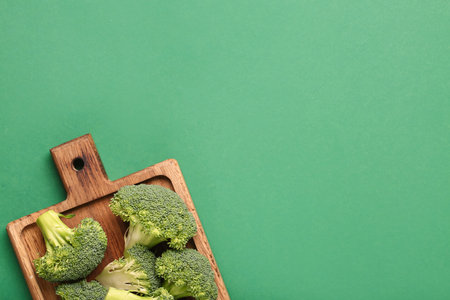 Wooden board with fresh broccoli cabbages on green backgroundの写真素材