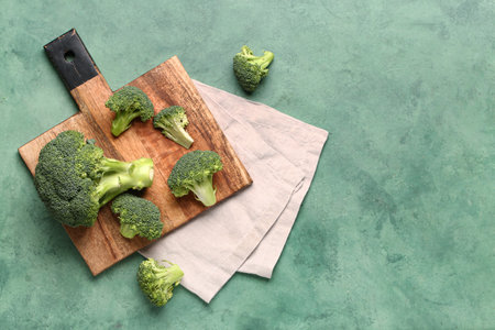 Wooden board with fresh broccoli cabbages on green backgroundの写真素材