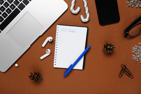 Notebook with empty to do list, laptop and mobile phone on brown backgroundの写真素材