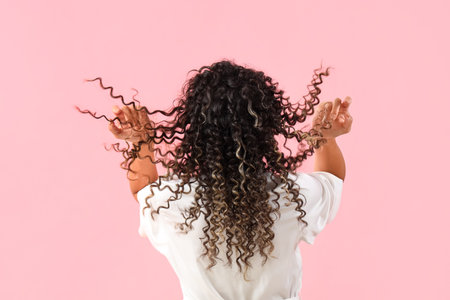 Young African-American woman with beautiful hair on pink background, back viewの写真素材