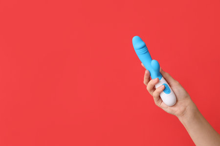 Female hand with vibrator on red backgroundの写真素材