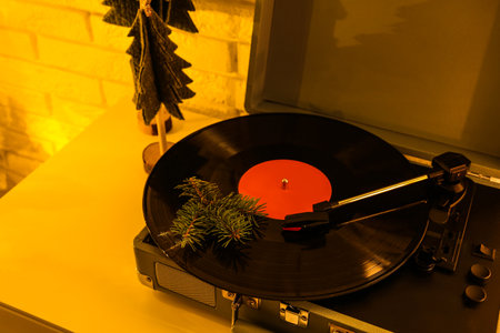 Record player with vinyl disc and fir tree branch in living room at evening, closeupの写真素材