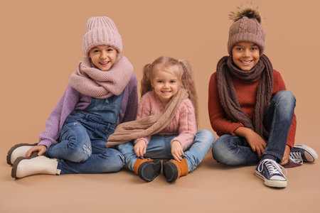 Cute children in winter clothes on beige backgroundの写真素材