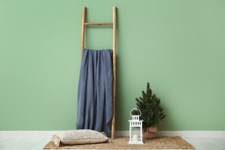 Lantern and small Christmas tree on floor near green wallの写真素材