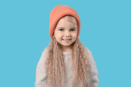 Cute little girl in warm hat on blue backgroundの写真素材
