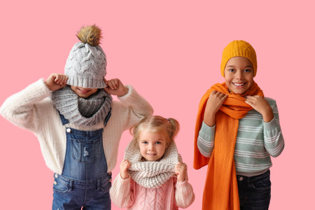 Cute children in winter clothes on pink backgroundの写真素材