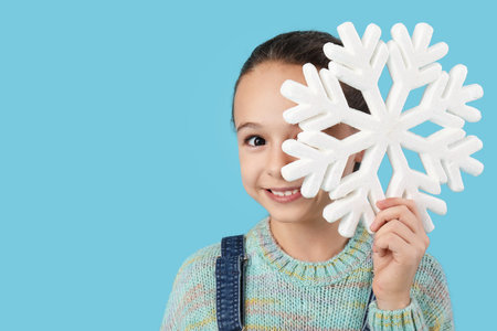 Cute little girl with decorative snowflake on blue backgroundの写真素材