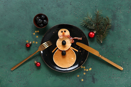 Plate with pancakes in the shape of snowman on green table. Christmas celebrationの写真素材