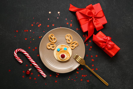 Plate with pancake in shape of reindeer on black table. Christmas celebrationの写真素材