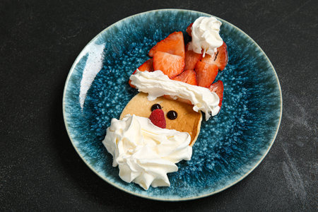 Plate with pancake in the shape of Santa on black table. Christmas celebrationの写真素材