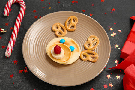 Plate with pancake in shape of reindeer on black table. Christmas celebrationの写真素材