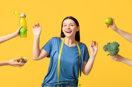 Beautiful young happy woman and hands with different healthy food on yellow background. Weight loss conceptの写真素材
