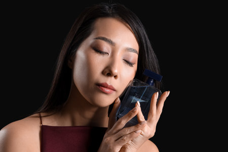 Beautiful Asian woman with perfume on dark background, closeupの写真素材