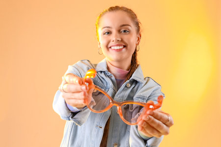 Young beautiful happy woman with stylish sunglasses on color backgroundの写真素材