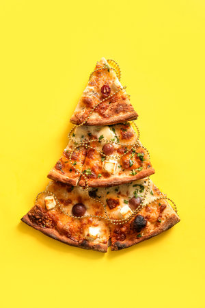 Christmas tree made of pizza slices and decor on yellow backgroundの写真素材
