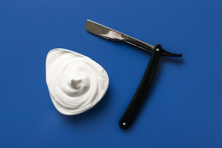 Bowl of shaving foam with razor on blue backgroundの写真素材