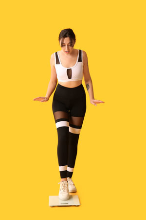 Beautiful shocked woman with scales on yellow background. Weight loss concept