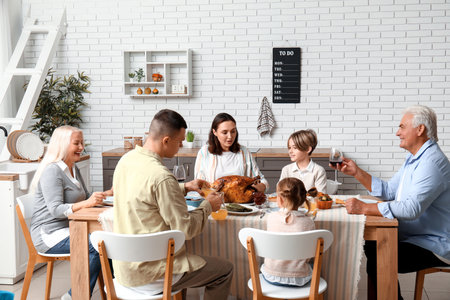 Happy family having dinner at festive table on Thanksgiving Dayの写真素材