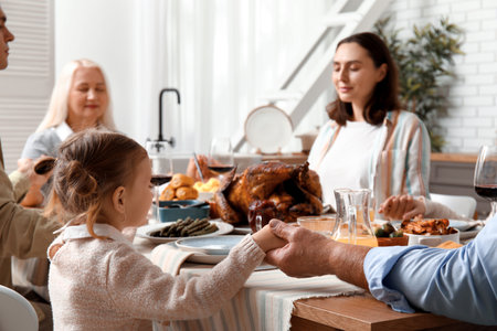 Happy family praying before dinner at festive table on Thanksgiving Dayの写真素材