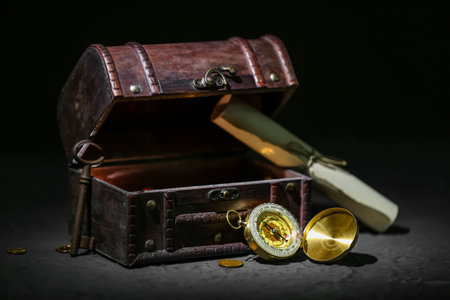 Old chest with treasures, key, scroll and compass on grunge black backgroundの写真素材