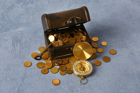 Old chest with coins, compass and key on blue grunge backgroundの写真素材