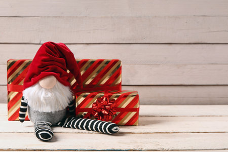 Christmas gnome with gift boxes on white wooden backgroundの写真素材